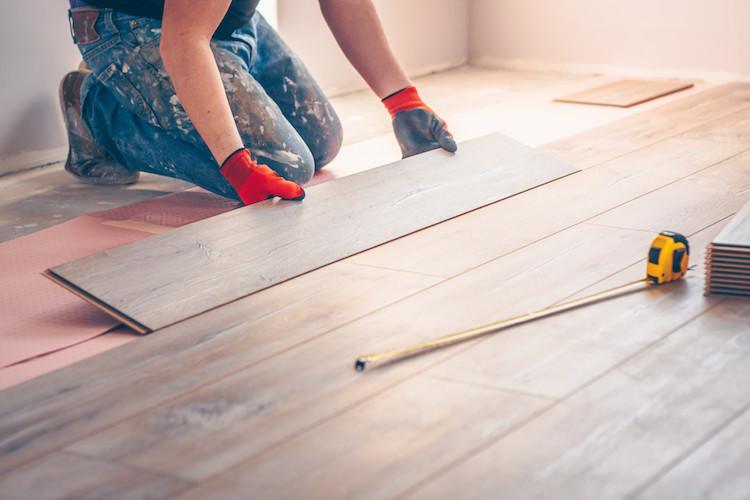 Worker installing new wooden floor tiles