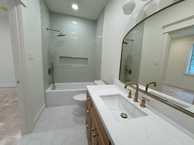 Finished bathroom with light green picket-tile shower, white quartz vanity and brushed gold fixtures - second story addition in Houston, TX
