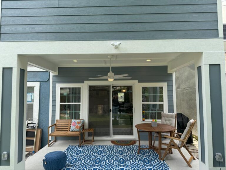 Finished covered back patio with ceiling fan, sliding glass doors, wood dining set and blue patterned rug - second story addition in Houston, TX
