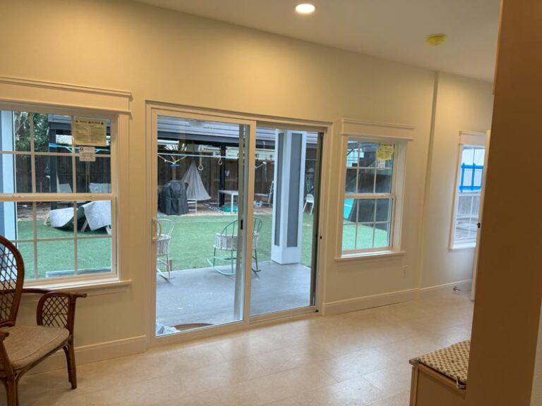 Living room interior with new sliding glass doors and windows looking onto the covered patio and lawn - second story addition in Houston, TX