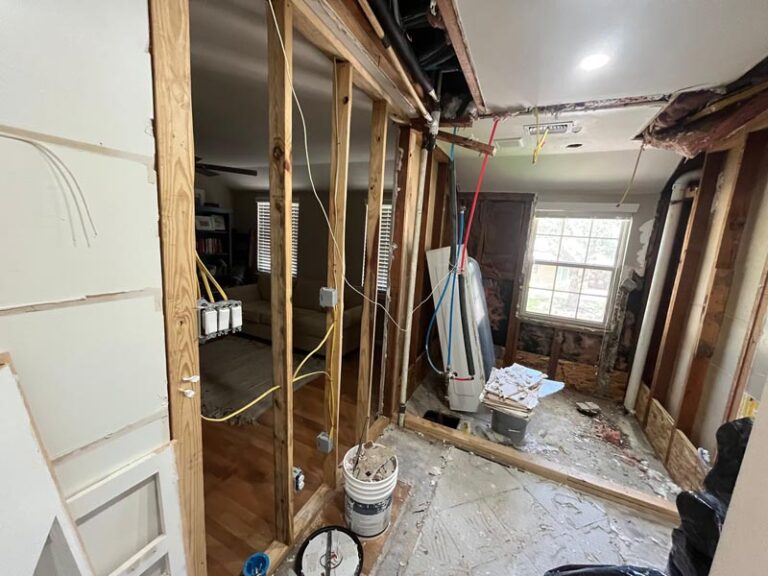 Bathroom demolished to wood studs during tear-out, with exposed framing, ceiling opening and construction debris - bathroom renovation in
