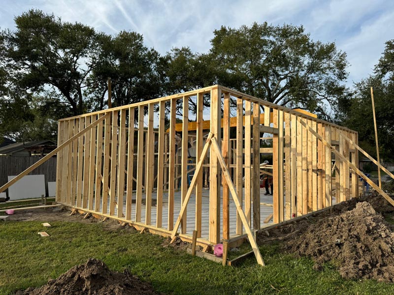 Early stage wood framing showing wall studs and roof truss structure for Houston garage