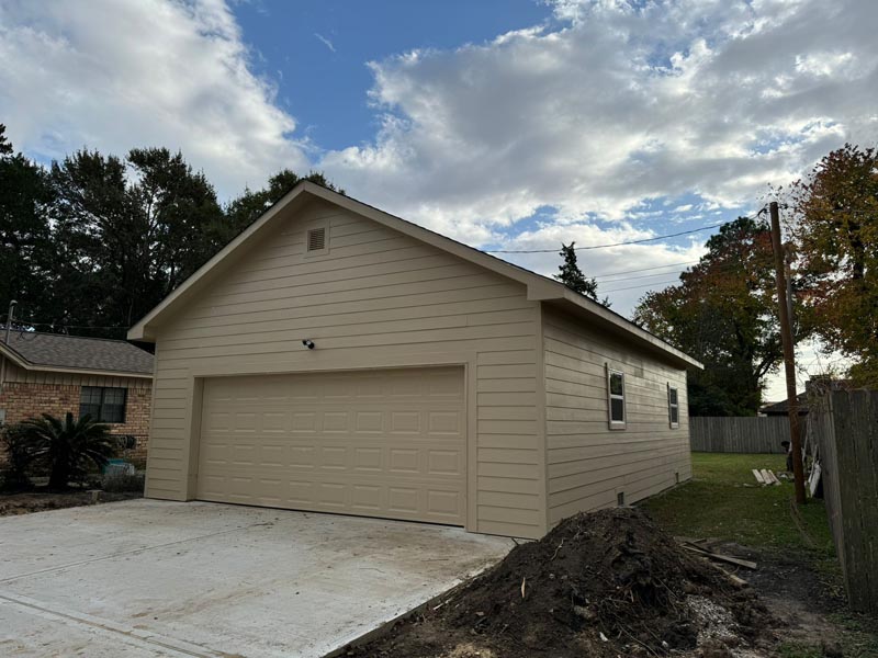 Completed 900 sq ft detached garage with beige lap siding and two-car door in Houston neighborhood