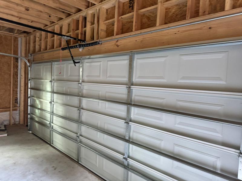 Interior garage door installation showing track system and automatic opener mechanism