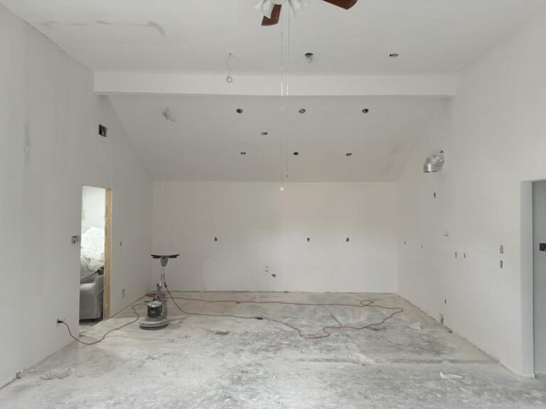 Gutted kitchen space with bare drywall and floor grinder before build-out - kitchen remodeling in Houston, TX