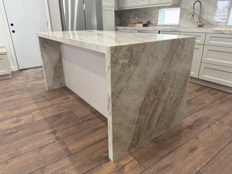 Close-up of quartzite waterfall island panels over wood-look plank floor - kitchen remodeling in Houston, TX