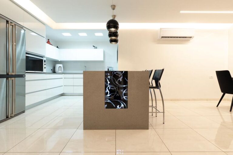 Kitchen island with black scrollwork accent panel, quartz countertop, bar stools, and stainless French-door refrigerator - modern kitchen