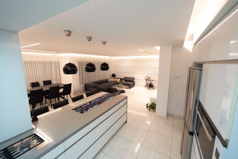 Kitchen island with built-in gas cooktop and gray countertop looking out to the open living and dining area - modern kitchen remodel in Houston,