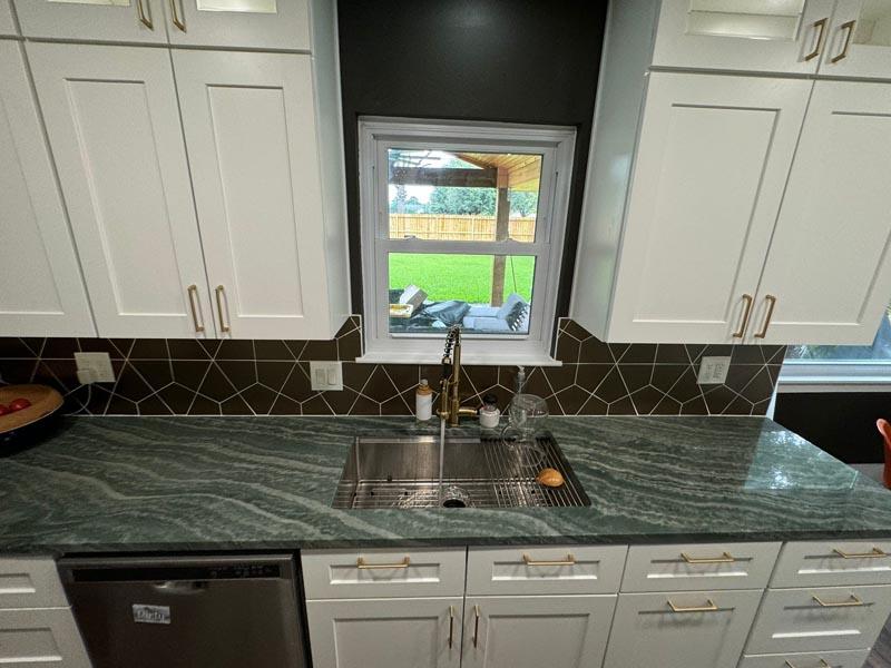 Undermount sink installation with dark geometric backsplash tile in budget-friendly Houston kitchen renovation