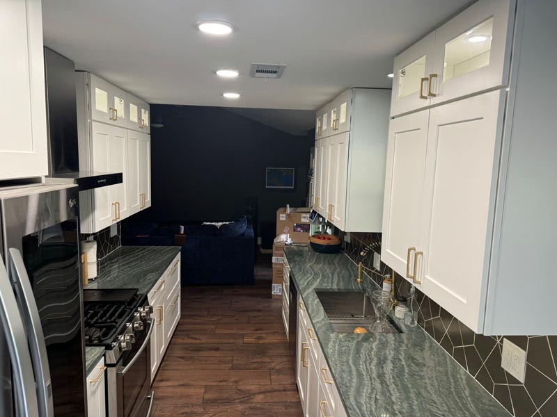 Galley style kitchen remodel Houston TX with white shaker cabinets dark countertops and LED recessed lighting