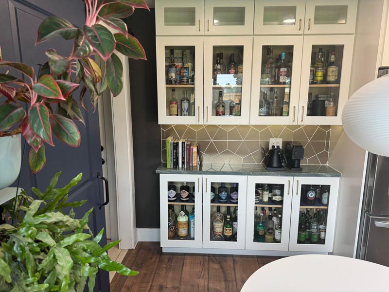 Elegant glass cabinet display for home bar area in affordable Houston kitchen renovation with geometric backsplash
