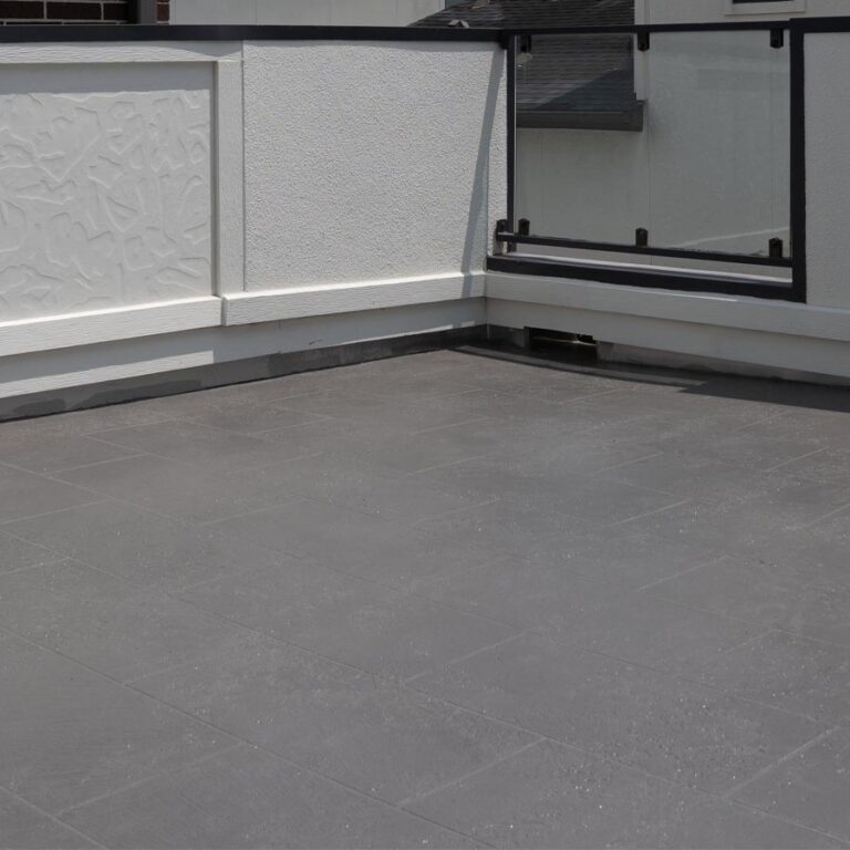 Waterproofed balcony deck in gray tile finish with glass-panel railing and white parapet, 77007 site