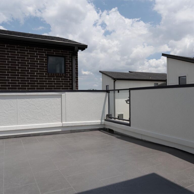 Finished rooftop balcony with gray tile-finish waterproof deck, white parapet and glass railing, 77007 site