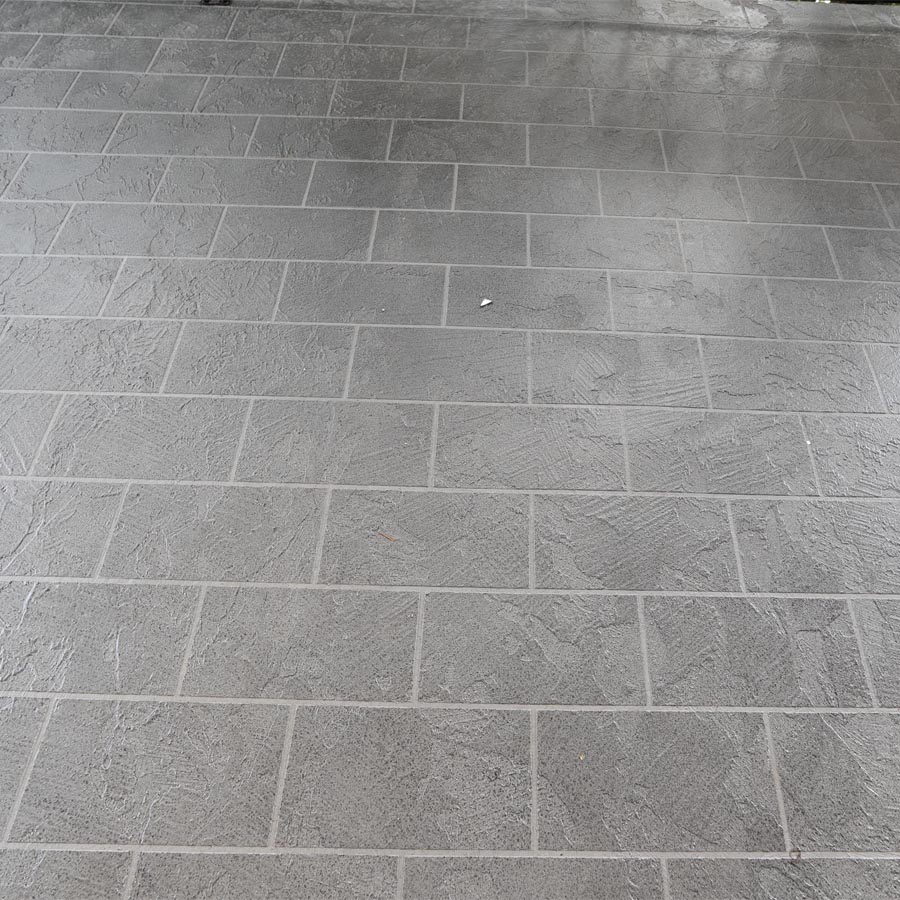 Close view of gray tile-patterned waterproof coating on a finished balcony deck in Seabrook, TX