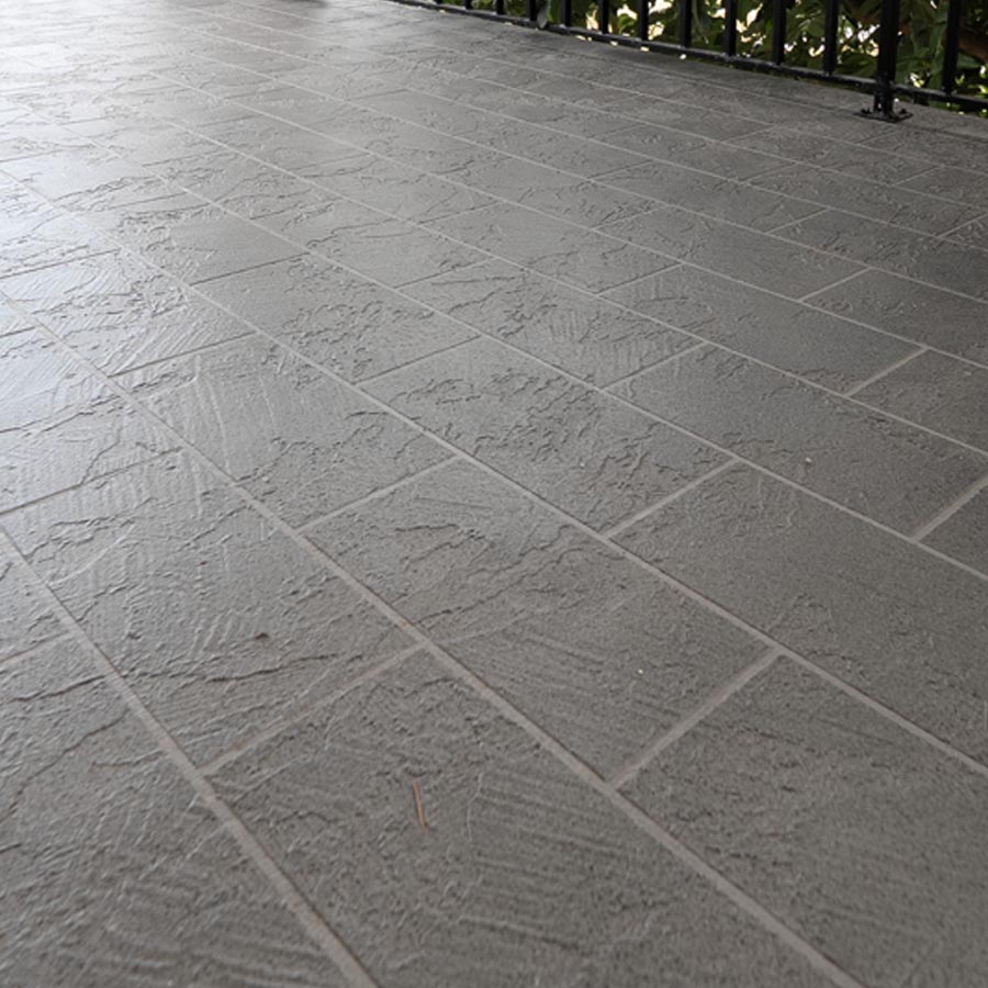 Angled view of textured gray waterproof coating on a rebuilt balcony deck in Seabrook, TX