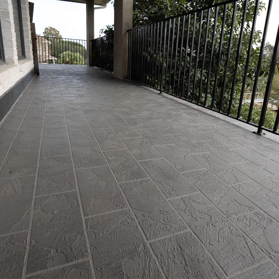 Covered balcony with textured waterproof deck coating, stone column, and iron railing in Seabrook, TX