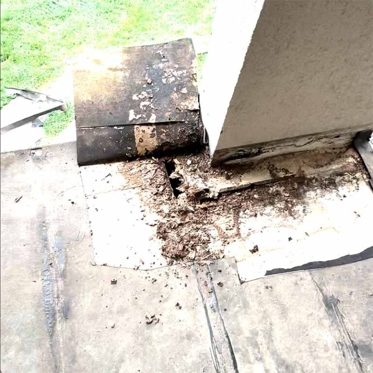 Rotted wood and debris at balcony column base exposed by failed waterproofing, 77586 site