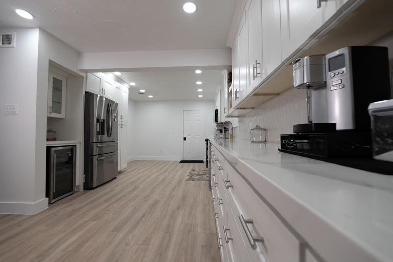 Full galley kitchen view with stainless appliances white cabinets and vinyl wood flooring Houston