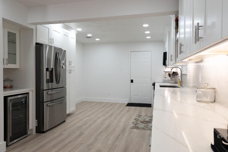 Galley kitchen remodel with French-door refrigerator white cabinets and wood-look flooring Houston