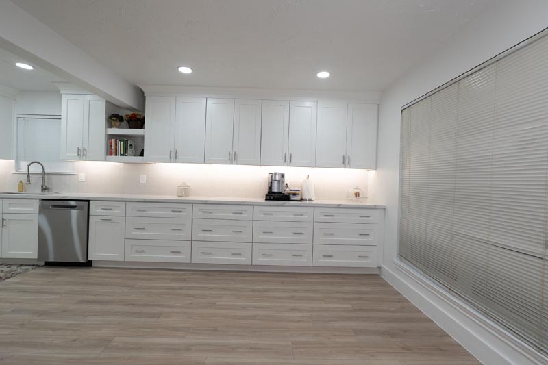 Kitchen storage wall with multiple drawer units under-cabinet lighting and luxury vinyl flooring