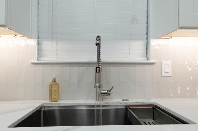 Kitchen sink window area with subway tile backsplash and modern pull-down faucet