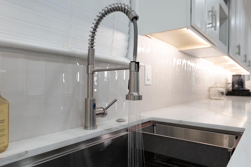 Professional kitchen faucet with spring coil and white subway tile backsplash Houston remodel