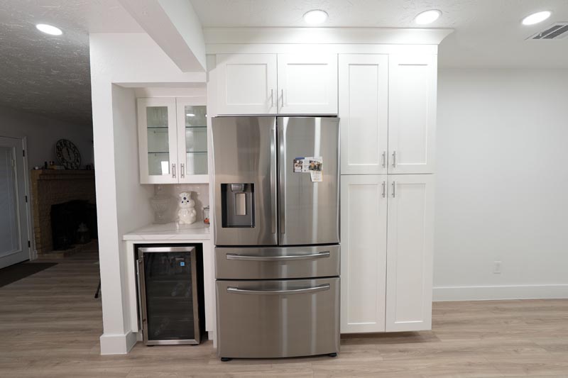 French-door refrigerator installation with floor-to-ceiling white cabinetry and built-in beverage center