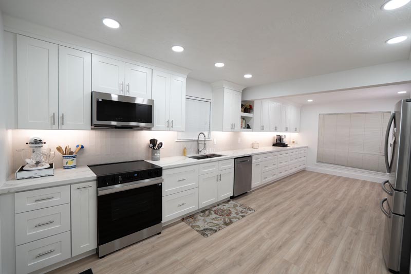 Modern kitchen with slide-in electric range white shaker cabinets and recessed lighting Houston
