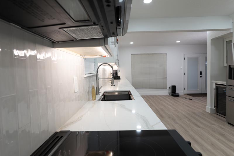 Kitchen island countertop with built-in electric range and white subway tile backsplash