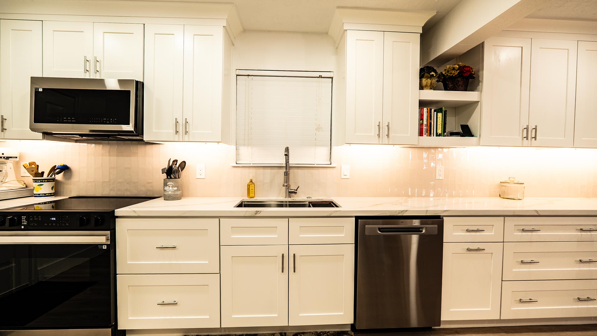 Remodeled kitchen with cream shaker cabinets, black range, and warm under-cabinet lighting in Pasadena, TX