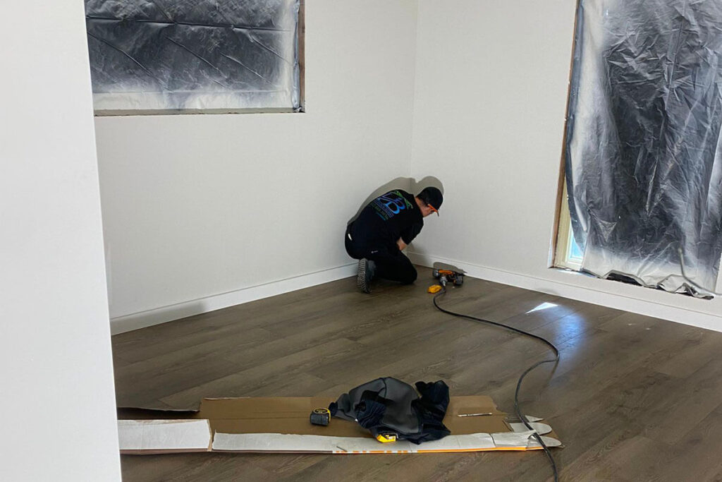 Contractor completing baseboard installation on sound-rated flooring in Midtown Houston condo remodel